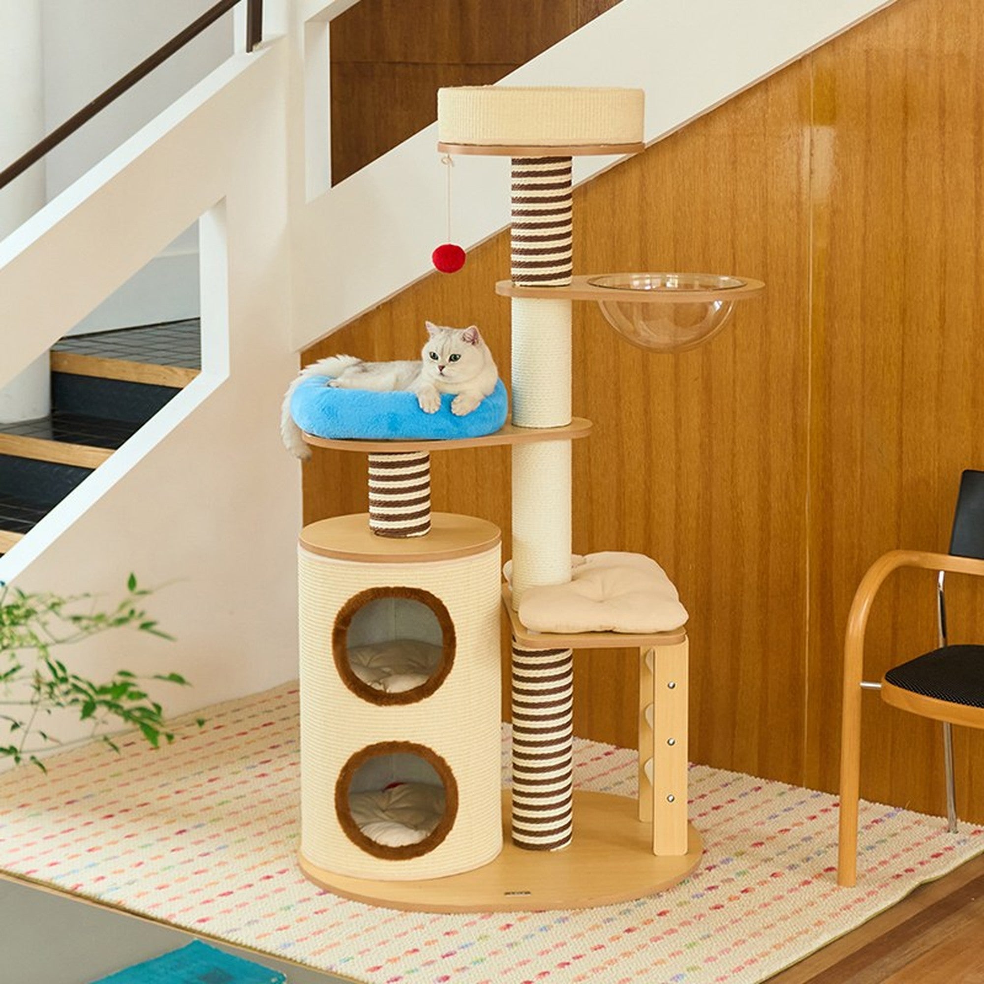 Cat lounging on the ZEZE 63-in double barrel wood cat tree by a staircase