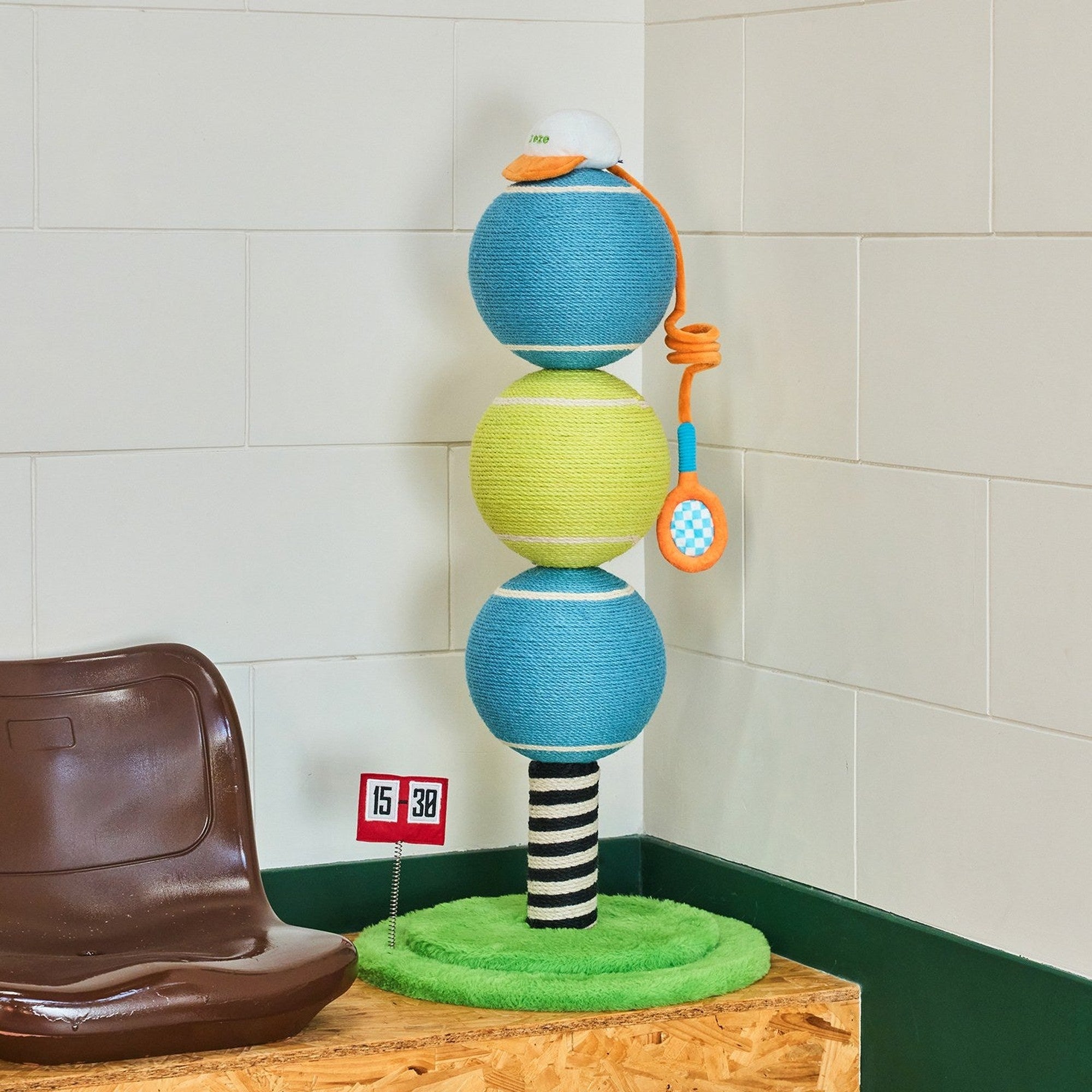 Ace tennis ball scratching post on a wooden platform beside a stadium seat