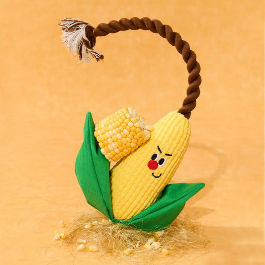 Corny corn toy standing on straw with a real corn cob