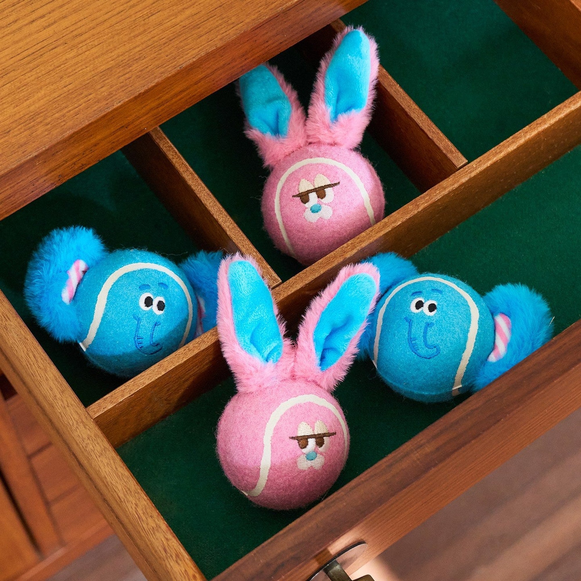 Dottie and Bonnie plush tennis balls in a wooden drawer