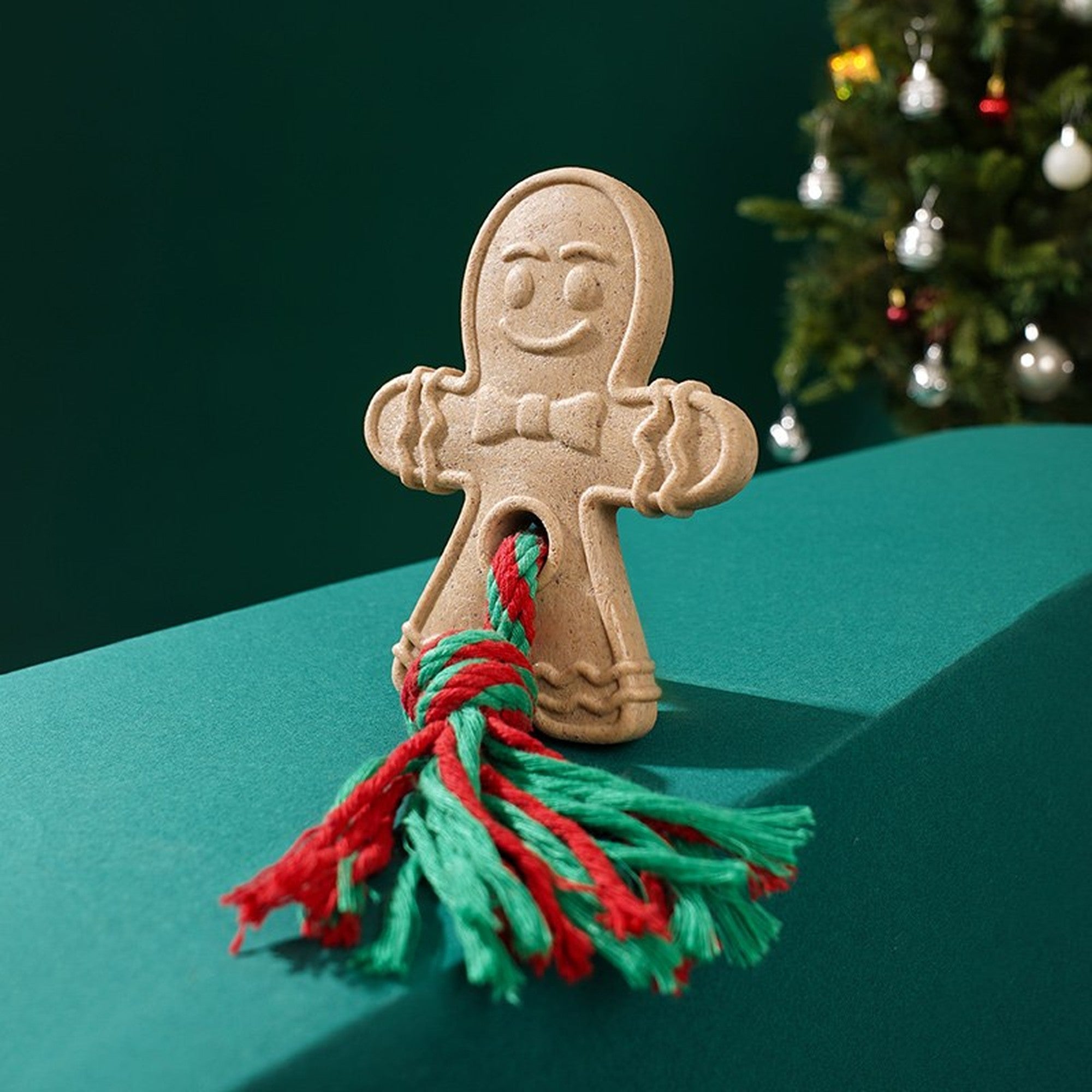 Gingerbread Man chew toy standing by a Christmas tree
