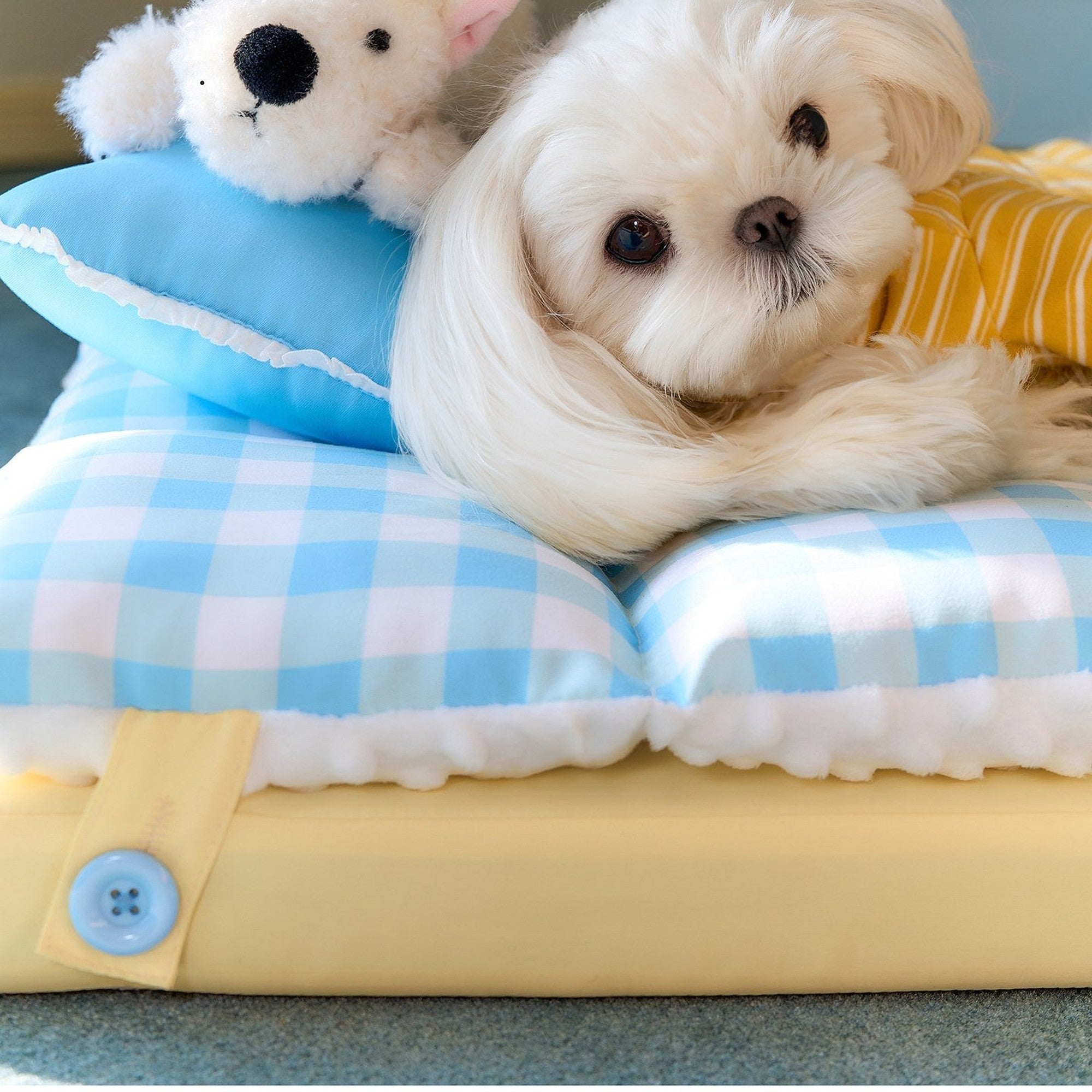 Maltese resting beside the plush puppy on the mini pillow