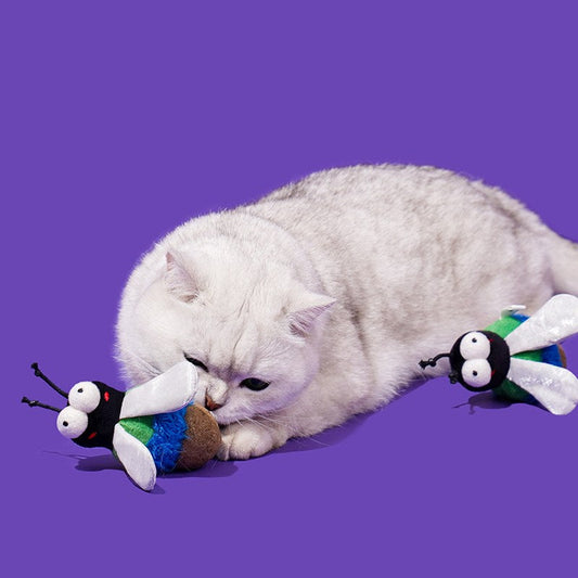 Cat lying down and sniffing a Green Fly toy