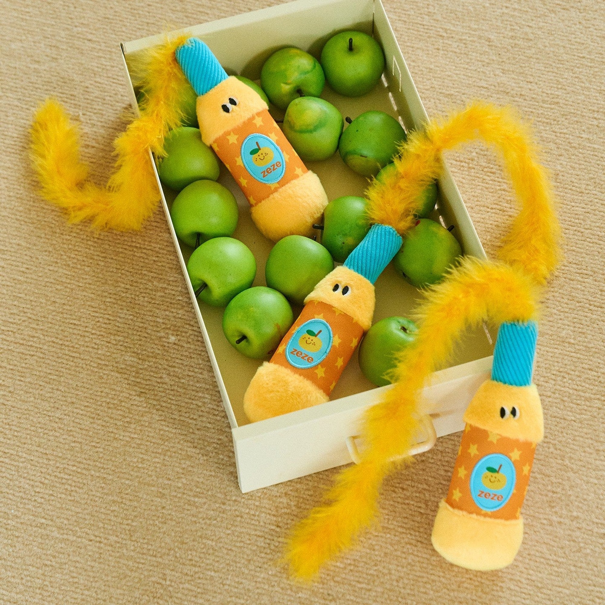 Orange Popper toys in a crate of green apples