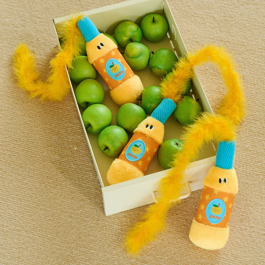 Orange Popper toys in a crate of green apples