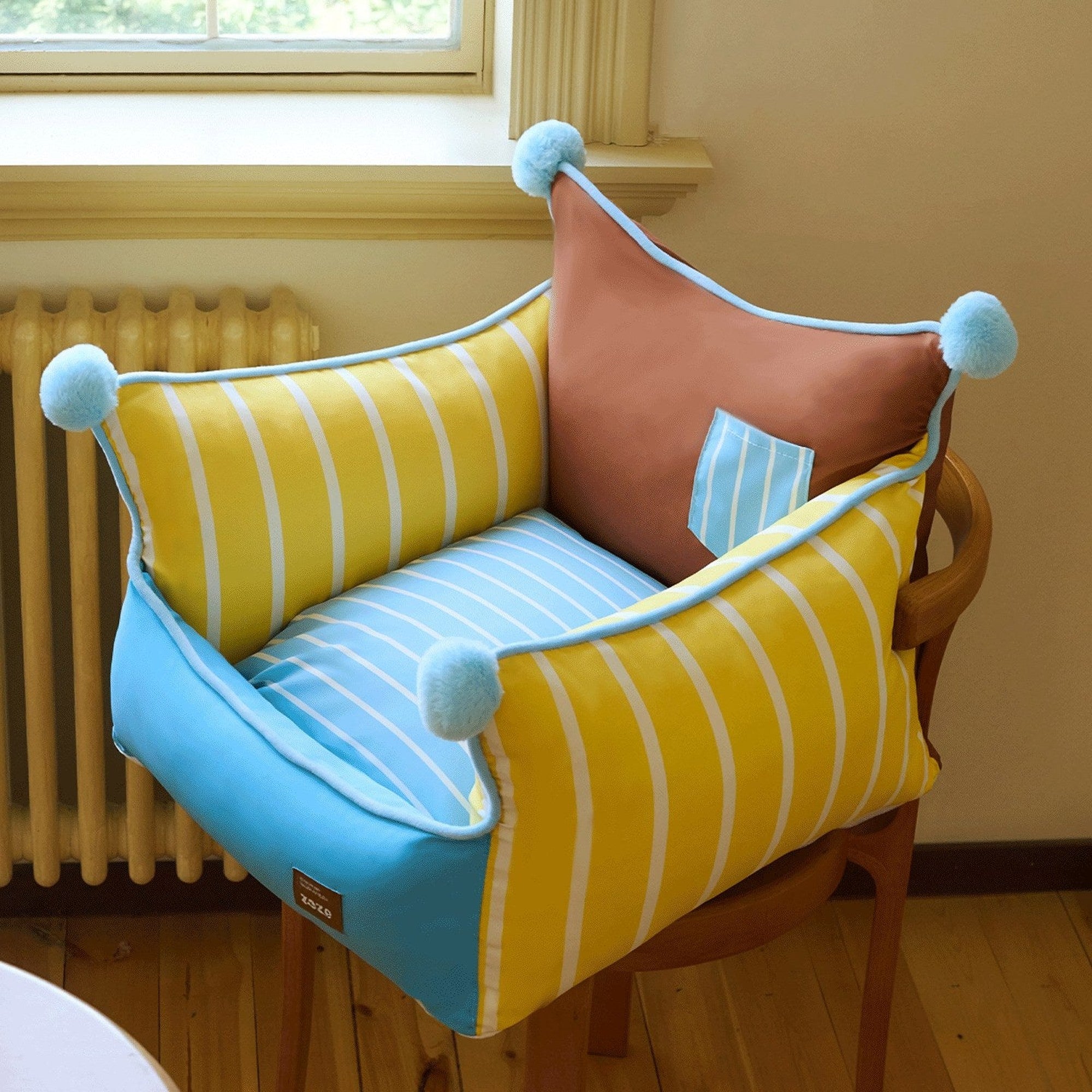 Pompom pet sofa on a wooden chair by a sunny window