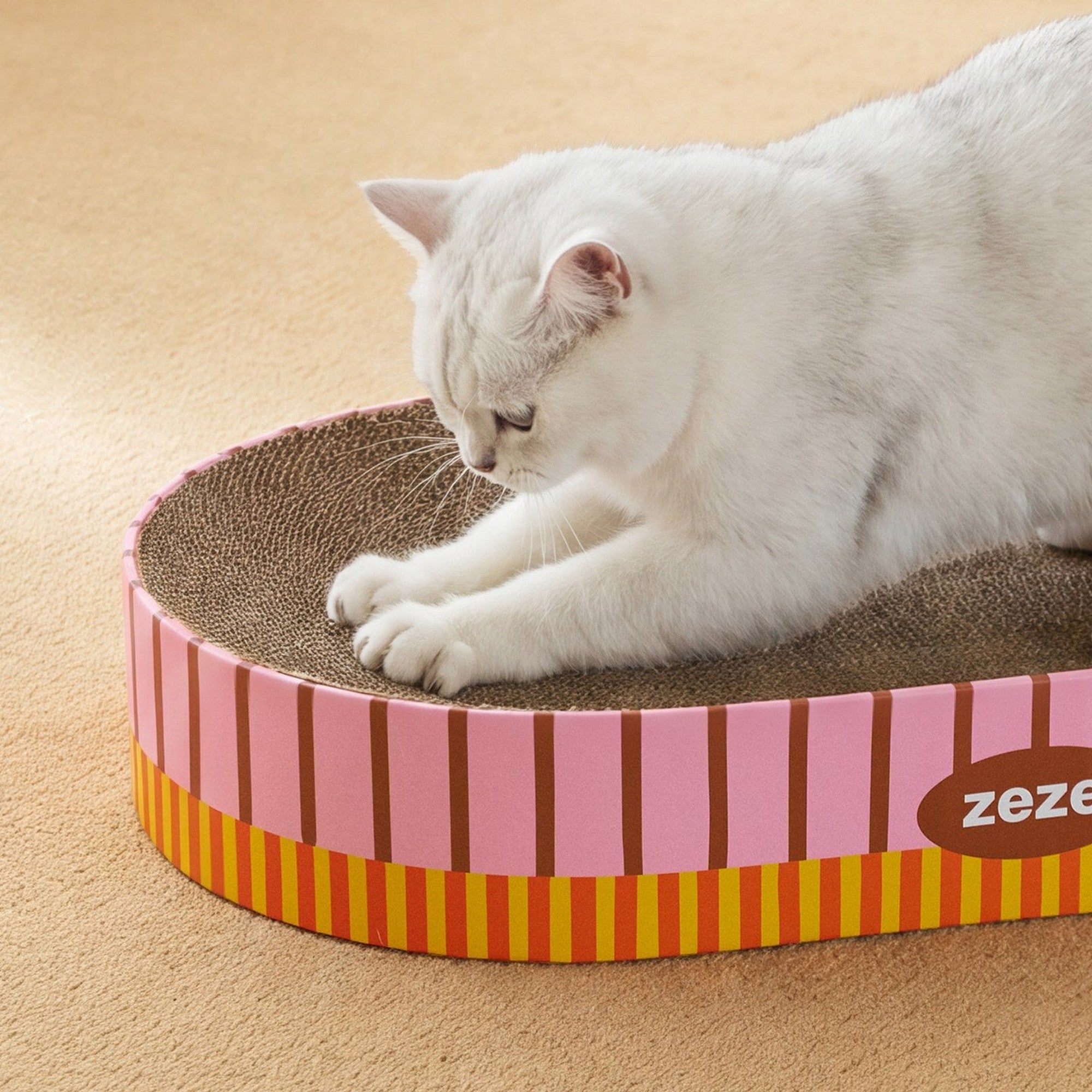White cat scratching the ZEZE Retro Stripe oval cardboard scratcher