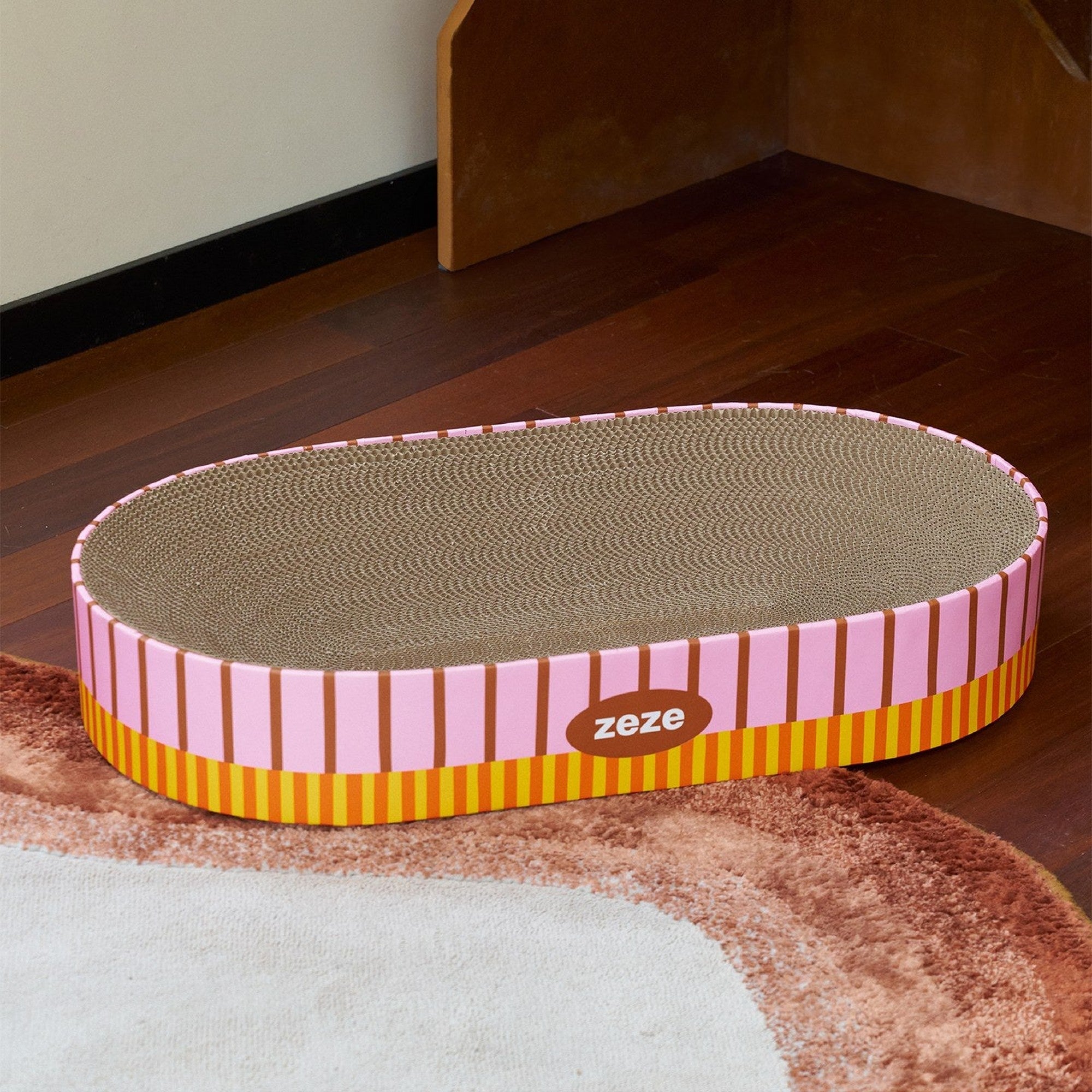 Oval scratcher on a rug by a wooden step