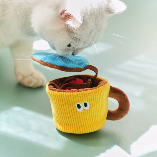 Cat sniffing under the lifted lid of the Snack Cup toy