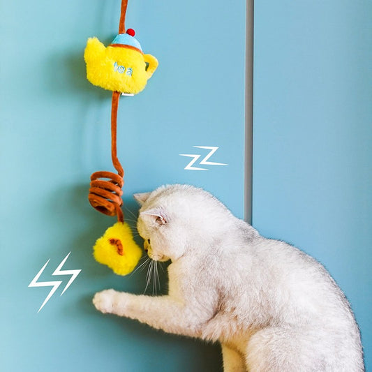 White cat swatting a Tea Time teapot toy hanging on a door