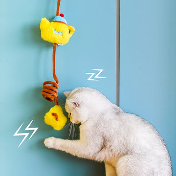 White cat swatting the ZEZE Tea Time yellow teapot hanging toy on a door